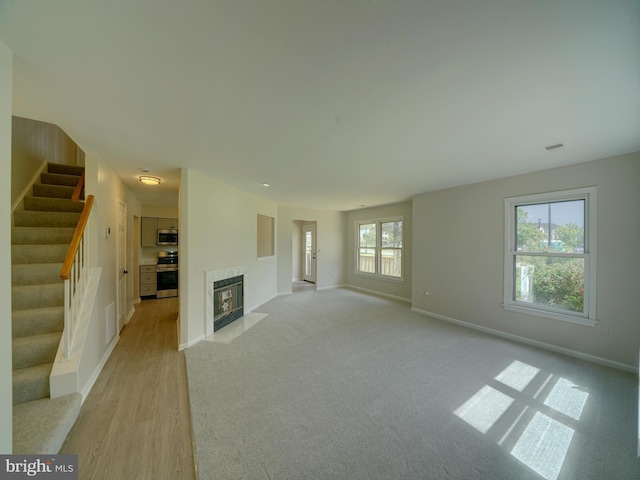9309 Player Dr Unit 116, Laurel, MD 20708 - unfurnished living room featuring stairs, baseboards, a fireplace, light wood finished floors, and light carpet