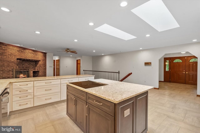 10060 Hampton Rd, Fairfax Station, VA 22039 - kitchen featuring a fireplace, a skylight, black electric stovetop, light stone countertops, and recessed lighting