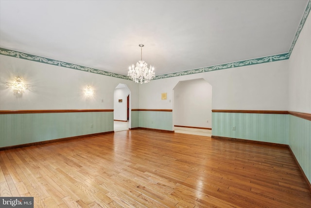 10060 Hampton Rd, Fairfax Station, VA 22039 - empty room featuring arched walkways, wood-type flooring, a chandelier, and a wainscoted wall