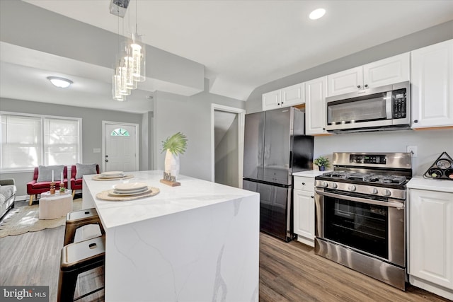 1076 Tunbridge Rd, Baltimore, MD 21212 - kitchen featuring stainless steel appliances, white cabinets, wood finished floors, a breakfast bar area, and a center island