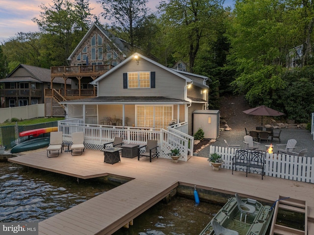 34 S Lake Dr, Lake Harmony, PA 18624 - back of house at dusk featuring a deck with water view, an outdoor living space with a fire pit, and view of scattered trees