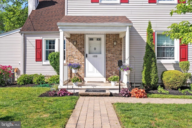 153 Sheridan Rd, Hamilton, NJ 08619 - view of exterior entry with a chimney, a yard, brick siding, and a shingled roof