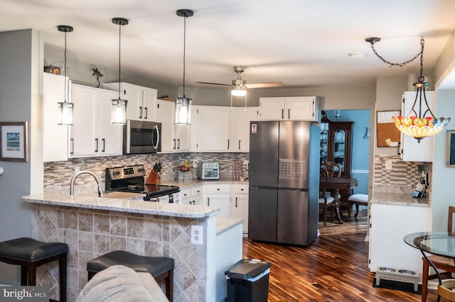 9348 Amaryllis Ave, Manassas, VA 20110 - kitchen with stainless steel appliances, a peninsula, light stone countertops, dark wood-type flooring, and backsplash