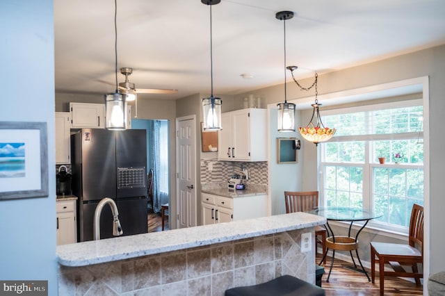 9348 Amaryllis Ave, Manassas, VA 20110 - kitchen with freestanding refrigerator, white cabinetry, backsplash, light stone counters, and wood finished floors