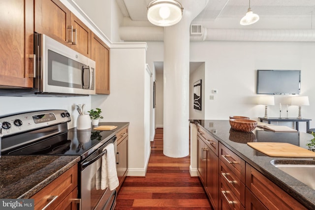 2429 Locust St Unit 504, Philadelphia, PA 19103 - kitchen featuring stainless steel appliances, dark wood-style flooring, brown cabinetry, dark stone counters, and hanging light fixtures