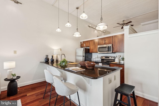 2429 Locust St Unit 504, Philadelphia, PA 19103 - kitchen with stainless steel appliances, a breakfast bar area, baseboards, brown cabinetry, and dark wood-type flooring