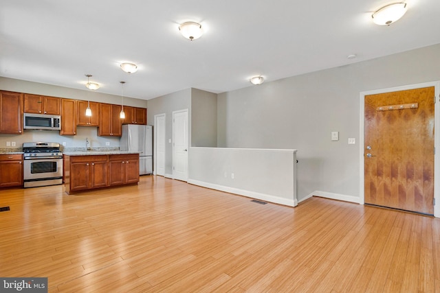 3318 Sherman Ave NW Unit 104, Washington, DC 20010 - kitchen with stainless steel appliances, light wood finished floors, a sink, baseboards, and brown cabinetry