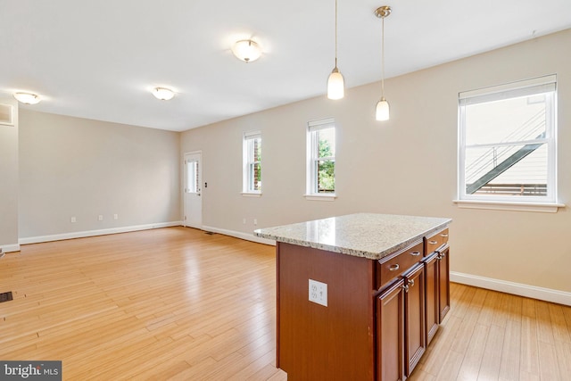 3318 Sherman Ave NW Unit 104, Washington, DC 20010 - kitchen featuring brown cabinetry, hanging light fixtures, baseboards, light wood-type flooring, and light stone countertops