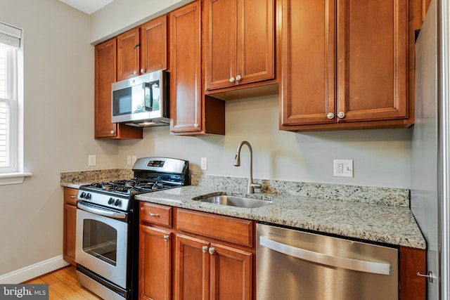 3318 Sherman Ave NW Unit 104, Washington, DC 20010 - kitchen with appliances with stainless steel finishes, a sink, light wood-style flooring, and light stone countertops