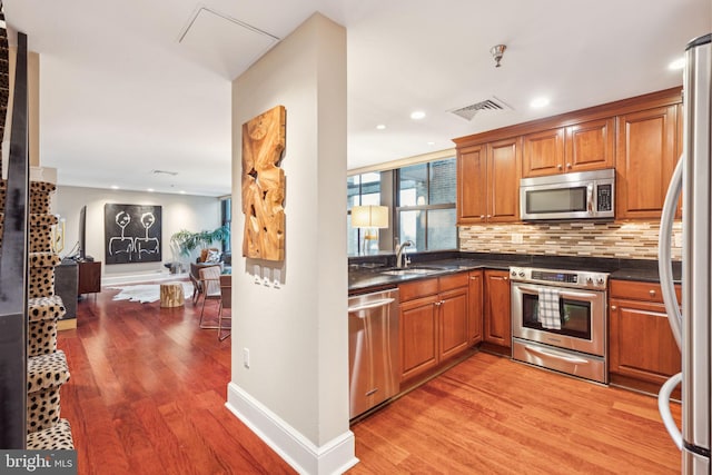 1500 Chestnut St Unit 20K, Philadelphia, PA 19102 - kitchen featuring appliances with stainless steel finishes, light wood-type flooring, brown cabinets, decorative backsplash, and recessed lighting