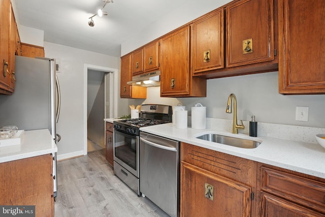 711 Avon Pl, Alexandria, VA 22314 - kitchen with appliances with stainless steel finishes, a sink, under cabinet range hood, brown cabinetry, and light wood-type flooring