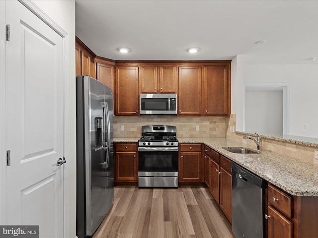 24258 Zinfandel Ln Unit R303, Lewes, DE 19958 - kitchen with appliances with stainless steel finishes, a sink, light wood-style floors, light stone counters, and decorative backsplash