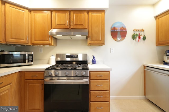 218 Independence Ave, State College, PA 16801 - kitchen with appliances with stainless steel finishes, under cabinet range hood, light countertops, baseboards, and brown cabinets