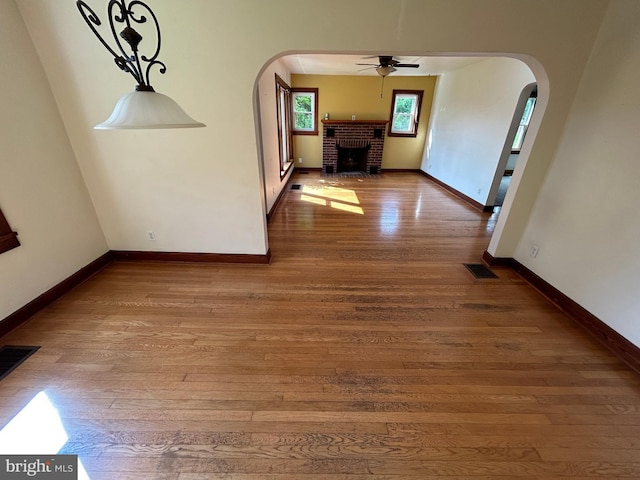 4599 Carlisle Rd, Gardners, PA 17324 - unfurnished dining area with arched walkways, a brick fireplace, ceiling fan, and wood finished floors