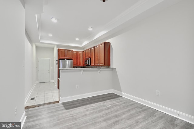 1129 Washington Blvd, Baltimore, MD 21230 - kitchen featuring stainless steel appliances, light wood finished floors, a peninsula, crown molding, and a raised ceiling