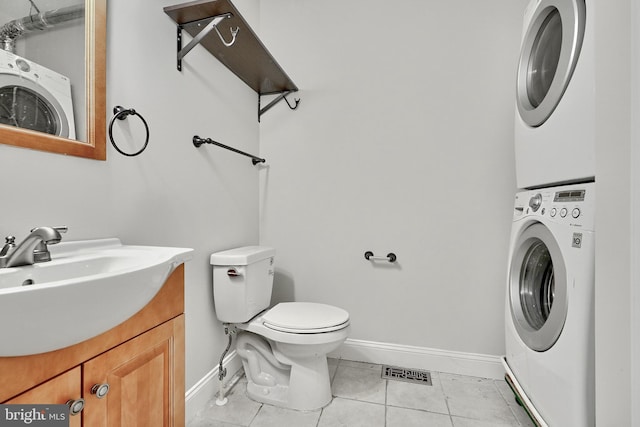 1129 Washington Blvd, Baltimore, MD 21230 - bathroom featuring stacked washer and clothes dryer, baseboards, toilet, tile patterned flooring, and vanity