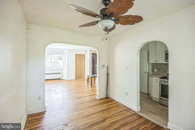 1338 Decatur St, Camden, NJ 08104 - empty room with radiator heating unit, arched walkways, a ceiling fan, and light wood-type flooring
