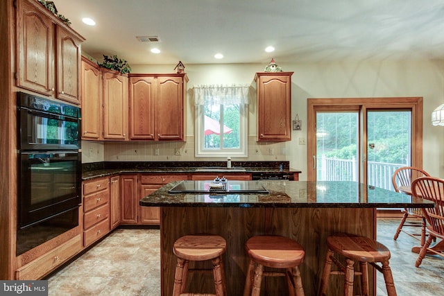 235 Amherst Dr, Doylestown, PA 18901 - kitchen with black appliances, a kitchen bar, a warming drawer, dark stone countertops, and a sink