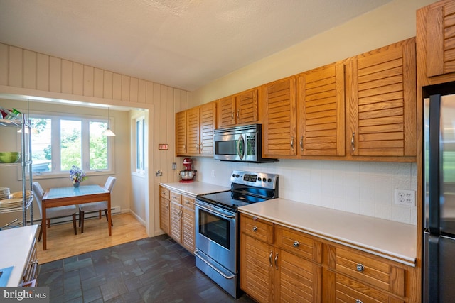 1272 Penfield Rd, State College, PA 16801 - kitchen featuring appliances with stainless steel finishes, backsplash, light countertops, dark stone finish flooring, and brown cabinetry