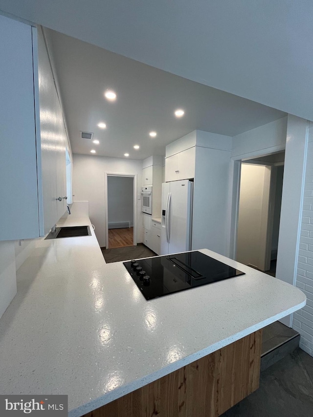 905 Dunellen Dr, Towson, MD 21286 - kitchen with white appliances, recessed lighting, white cabinetry, a sink, and a peninsula