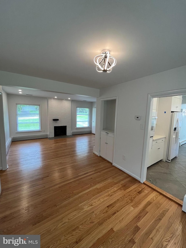 905 Dunellen Dr, Towson, MD 21286 - unfurnished living room featuring wood finished floors, a chandelier, baseboards, a baseboard radiator, and a brick fireplace