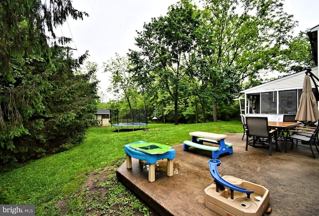 16 Grove Cir, Sellersville, PA 18960 - view of green lawn featuring a trampoline, outdoor dining area, a patio area, a sunroom, and view of scattered trees