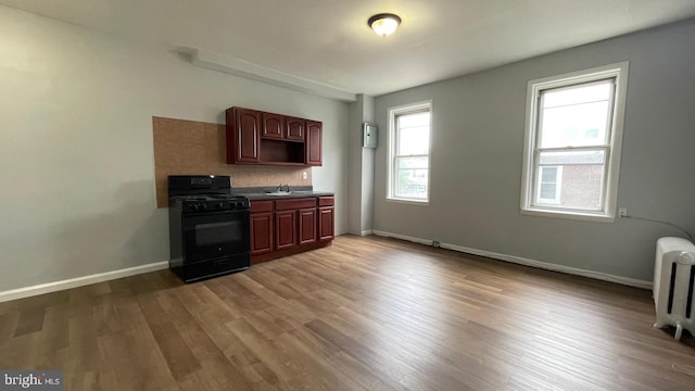 4937 N 13th St, Philadelphia, PA 19141 - kitchen featuring black range with gas stovetop, a sink, radiator, wood finished floors, and baseboards