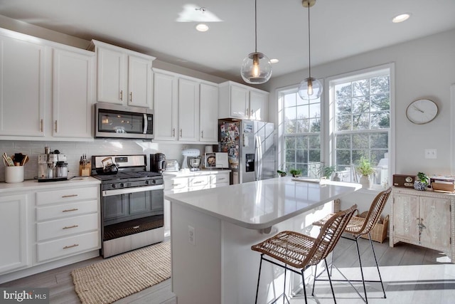 3402 Gentle Breeze Dr, Upper Marlboro, MD 20772 - kitchen with stainless steel appliances, white cabinetry, a kitchen breakfast bar, light countertops, and backsplash