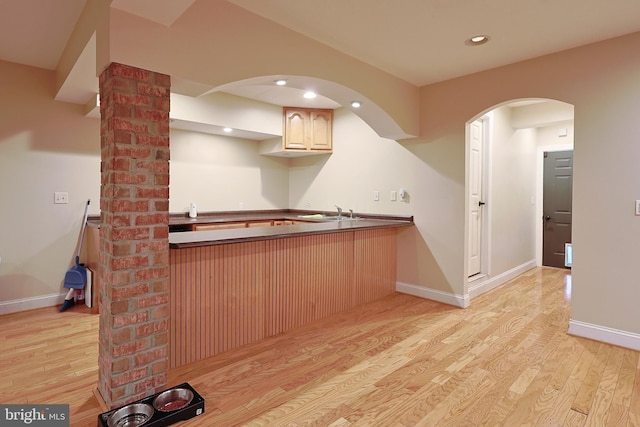 25 Mariner Ct, Ridgeley, WV 26753 - kitchen featuring light wood-style floors, a peninsula, dark countertops, arched walkways, and baseboards