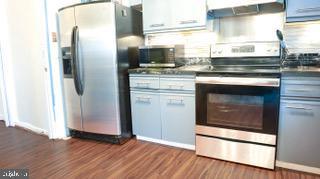 22 Erbitea Ln, New Castle, DE 19720 - kitchen with appliances with stainless steel finishes, dark wood-style flooring, and exhaust hood
