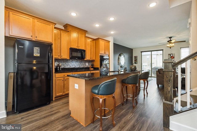 45394 Daveno Sq, Sterling, VA 20164 - kitchen with black appliances, dark wood finished floors, a breakfast bar, a center island with sink, and recessed lighting