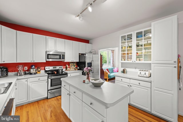 419 Westside Station Dr, Winchester, VA 22601 - kitchen with stainless steel appliances, light countertops, white cabinets, track lighting, and glass insert cabinets