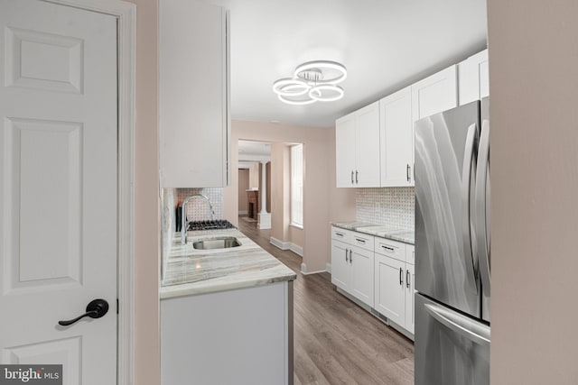 2032 S 21st St, Philadelphia, PA 19145 - kitchen featuring freestanding refrigerator, a sink, decorative backsplash, light wood-style floors, and white cabinetry