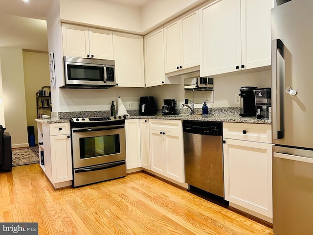 1314 Massachusetts Ave NW Unit G04, Washington, DC 20005 - kitchen featuring stainless steel appliances, light wood finished floors, stone counters, and white cabinets