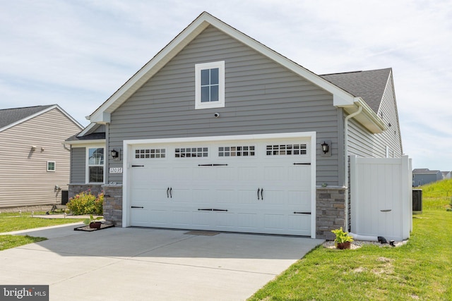12037 Angora Dr, King George, VA 22485 - view of property exterior with stone siding, concrete driveway, central AC unit, an attached garage, and a lawn