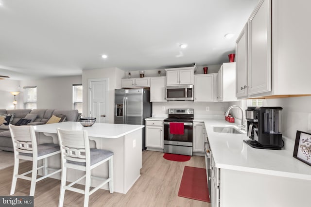 12037 Angora Dr, King George, VA 22485 - kitchen with stainless steel appliances, a sink, a breakfast bar area, light countertops, and light wood-style floors