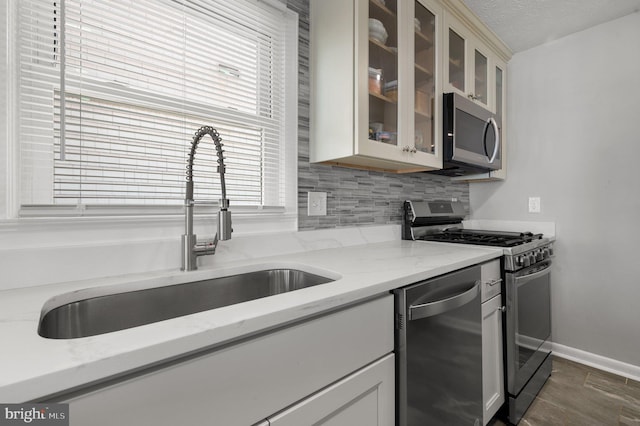 106 Lighthouse Dr, Hampton, VA 23664 - kitchen with appliances with stainless steel finishes, a sink, backsplash, glass insert cabinets, and light stone countertops