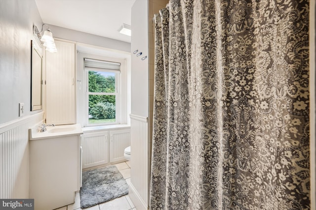 23274 Holly Park Dr, Preston, MD 21655 - full bathroom featuring toilet, vanity, wainscoting, tile patterned floors, and a decorative wall