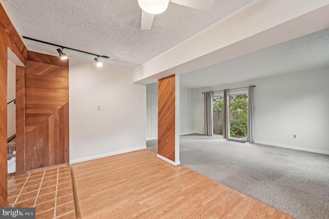 225 Dunlap Rd, Pasadena, MD 21122 - unfurnished living room featuring track lighting, a textured ceiling, baseboards, wood walls, and wood finished floors