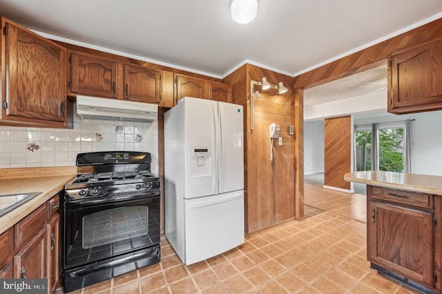225 Dunlap Rd, Pasadena, MD 21122 - kitchen featuring white refrigerator with ice dispenser, black range with gas stovetop, light countertops, under cabinet range hood, and decorative backsplash