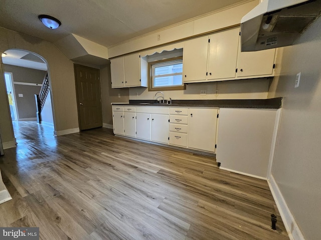 413 10th Ave, Altoona, PA 16602 - kitchen featuring under cabinet range hood, arched walkways, baseboards, dark countertops, and a sink