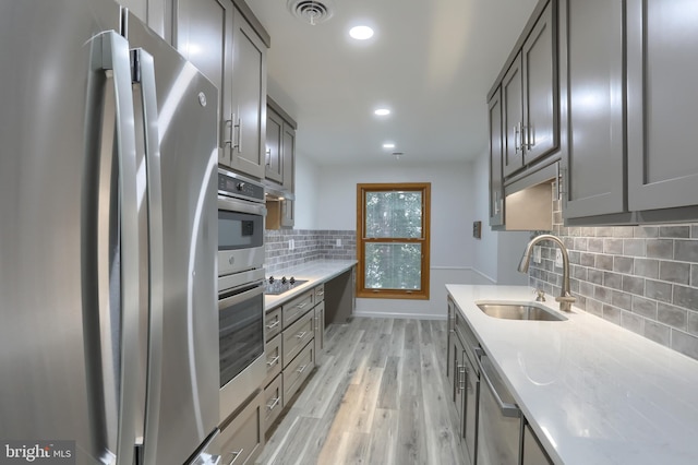69 Drexel Pl, New Cumberland, PA 17070 - kitchen featuring appliances with stainless steel finishes, a sink, gray cabinetry, light wood-type flooring, and decorative backsplash