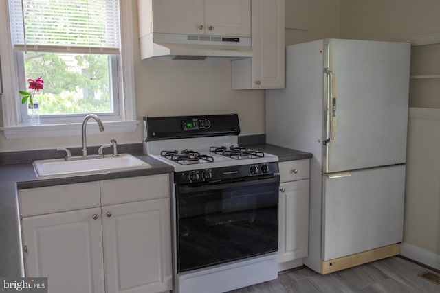 107 Bishops Ln, Baltimore, MD 21228 - kitchen featuring gas stove, under cabinet range hood, freestanding refrigerator, a sink, and dark countertops