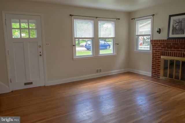 107 Bishops Ln, Baltimore, MD 21228 - unfurnished living room featuring wood finished floors, baseboards, and a brick fireplace