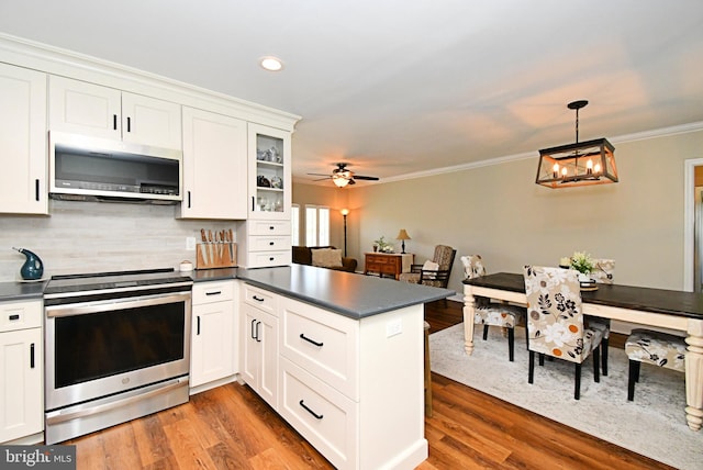 985 Jeffrey Dr, Southampton, PA 18966 - kitchen with appliances with stainless steel finishes, dark countertops, a peninsula, white cabinets, and ornamental molding