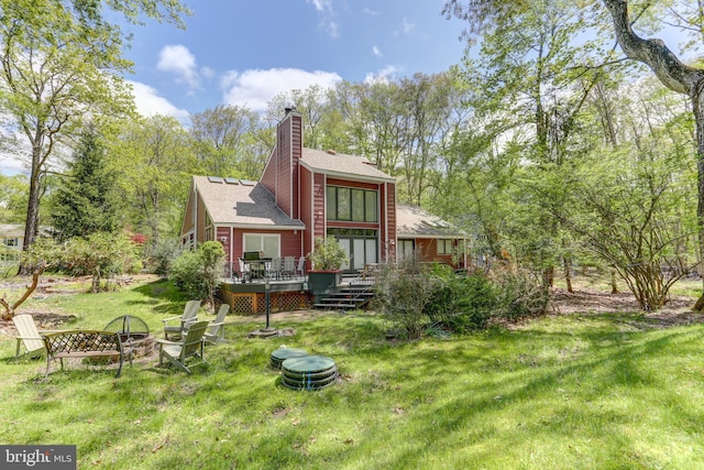 3217 Beech Ridge Dr, Pocono Summit, PA 18346 - back of house with an outdoor fire pit, a yard, a wooden deck, a chimney, and roof with shingles