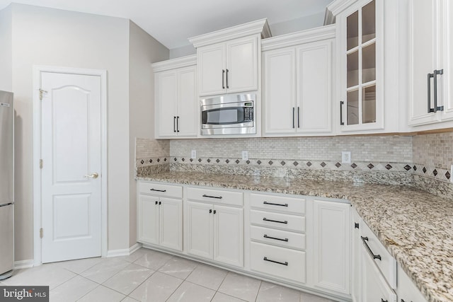 21934 Windover Dr, Broadlands, VA 20148 - kitchen with appliances with stainless steel finishes, tasteful backsplash, white cabinetry, glass insert cabinets, and light tile patterned floors
