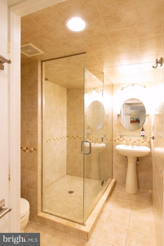 6306 Blackburn Ct, Baltimore, MD 21212 - bathroom featuring tile patterned flooring, a stall shower, toilet, tile walls, and a sink