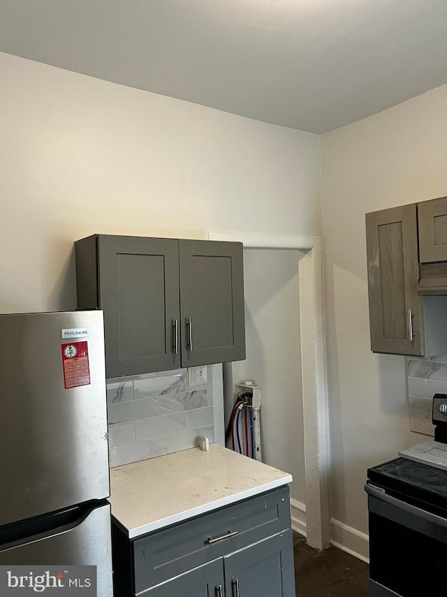 2208 W Oakdale St, Philadelphia, PA 19132 - kitchen featuring freestanding refrigerator, range, gray cabinets, decorative backsplash, and baseboards