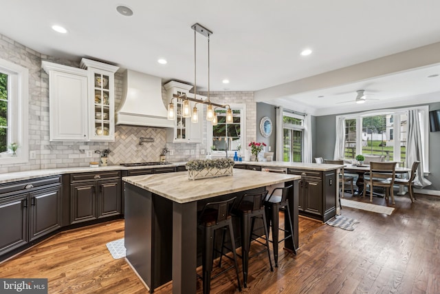 13128 Kahns Rd, Manassas, VA 20112 - kitchen featuring custom exhaust hood, a peninsula, a center island, plenty of natural light, and recessed lighting